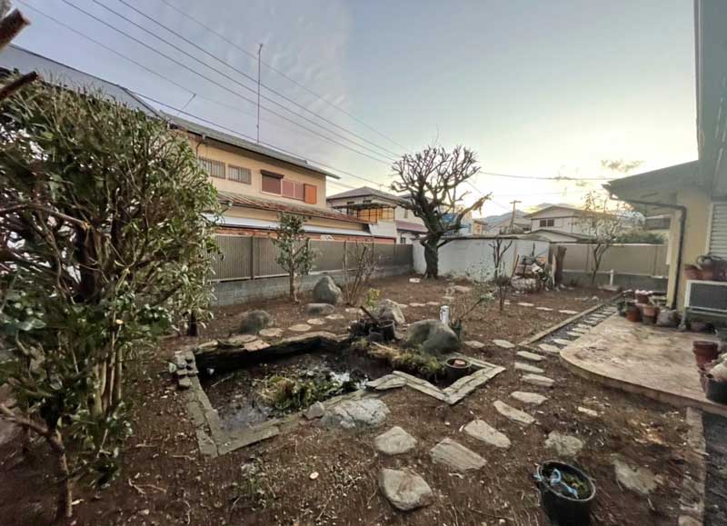 施工後のお庭。ツタを根元から除去し、26本の木々を伐採・剪定したことで、足元から石組みの池が再び姿を現した様子。
