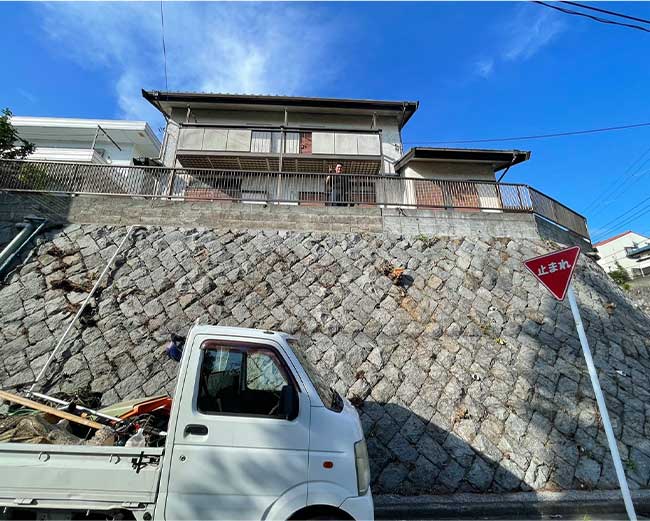 擁壁上の高木や壁の隙間から生えていた木を根元から伐採し、障害物がなくなりスッキリと安全になった通学路の様子。